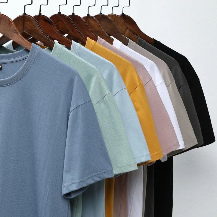 Colorful men’s t-shirts hanging in a row on wooden hangers at a men’s clothing store in kerala